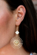 Load image into Gallery viewer, A white shell is tilted on its side and bordered by gold studs, giving way to a large gold sunburst dotted with a multicolored stone center; resulting in a whimsically radiant lure. Earring attaches to a standard fishhook fitting. As the stone elements in this piece are natural, some color variation is normal.  Sold a
