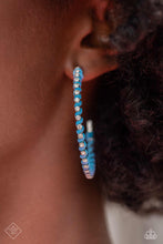 Load image into Gallery viewer, The outer edge of an oversized silver hoop is lined with classic white rhinestones, scattering sparkle in every direction. A strand of blue cording intricately twists and weaves in between the glitzy gems, adding a fearless pop of color to the design. Earring attaches to a standard post fitting. Hoop measures approximately 2″ in diameter.  Sold as one pair of hoop ea
