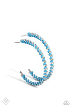 Load image into Gallery viewer, The outer edge of an oversized silver hoop is lined with classic white rhinestones, scattering sparkle in every direction. A strand of blue cording intricately twists and weaves in between the glitzy gems, adding a fearless pop of color to the design. Earring attaches to a standard post fitting. Hoop measures approximately 2″ in diameter.  Sold as one pair of hoop ea
