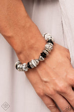 Load image into Gallery viewer, Featuring a black-dotted pattern, abstract white stone discs, black acrylic discs, and various silver discs and accents are threaded along an elastic stretchy band for a high-end, artisanal-inspired look. As the stone elements in this piece are natural, some color variation is normal.
