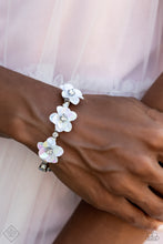 Load image into Gallery viewer, Shiny silver beads, white rhinestones in sleek silver frames, and varying sizes of iridescent gems in the same silver frames are threaded along a wire that coils around the wrist to create an infinity wrap style bracelet. At the center of the design, a trio of white iridescent flowers with white rhinestone centers emerges, adding a touch of whimsical color and three-dimensional texture. Due to its prismatic palette, color may vary.  Sold as one individual bracelet.
