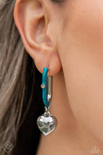 Load image into Gallery viewer, Featuring a solitaire white rhinestone embellishment, a silver heart charm swings from a glistening half turquoise-painted oblong silver hoop, creating a vivacious, charming display. Earring attaches to a standard post fitting. Hoop measures approximately 1&quot; in diameter.
