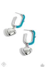 Load image into Gallery viewer, Featuring a solitaire white rhinestone embellishment, a silver heart charm swings from a glistening half turquoise-painted oblong silver hoop, creating a vivacious, charming display. Earring attaches to a standard post fitting. Hoop measures approximately 1&quot; in diameter.
