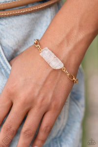 Delicately attached to a gold wire, a chiseled piece of clear white stone twists along a gold paperclip chain around the wrist, creating a decadently earthy centerpiece. Features an adjustable clasp closure.  Sold as one individual bracelet.