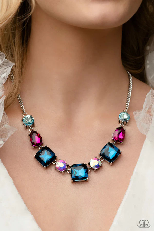 Encased within thick, pronged, elevated silver settings, a geometric collection of fuchsia, light blue, dark blue, and iridescent rhinestones, featured in square, teardrop, and round shapes coalesces down the neckline for a gritty, yet glamorous display. Features an adjustable clasp closure. Due to its prismatic palette, color may vary.  Sold as one individual necklace. Includes one pair of matching earrings.