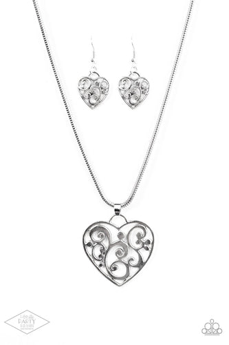 An airy heart swings from the bottom of shimmery silver cocoon chain, creating a whimsical pendant below the collar. Brushed in an antiqued shimmer, frilly filigree climbs the heart frame for a vintage inspired finish. Features an adjustable clasp closure.
