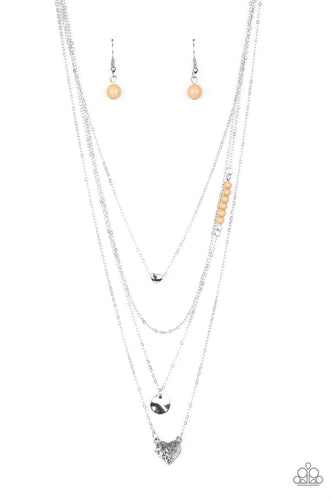 Shimmery silver layers cascade below the collar. Infused with hints of brown beading, dainty silver hearts and a delicately hammered silver disc swing from the bottoms of the chains for a whimsical finish. Features an adjustable clasp closure.