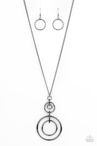 A series of shiny gunmetal hoops are threaded through glistening gunmetal fittings that connect into a dizzyingly stacked pendant at the end of a lengthened gunmetal chain. Features an adjustable clasp closure.