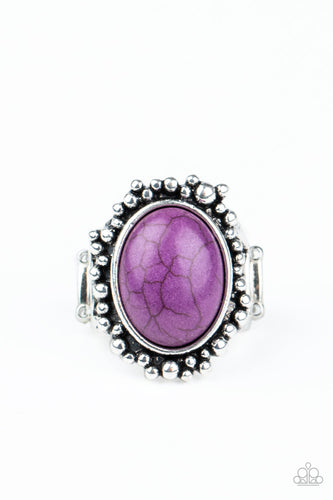 An oval Magenta Purple stone is pressed into a rustic silver frame radiating with antiqued silver studs, creating an earthy centerpiece atop the finger. Features a stretchy band for a flexible fit.