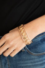 Load image into Gallery viewer, Flattened in sections, rows of glistening gold wire weave between two gold bars, creating a shimmery cuff around the wrist.
