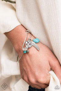 Featuring a shimmery silver feather charm, ornate silver beads and earthy turquoise stone beads glide along the fitted center of a dainty silver bangle-like bracelet for a whimsically charming look.