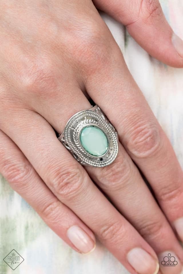 A dewy oval Blue Tint gem is pressed into the center of a textured silver frame, creating a raised centerpiece. Features a stretchy band for a flexible fit.