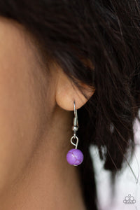A vivacious purple stone is pressed into a shimmery silver frame radiating with metallic rope-like texture, creating a bold pendant at the bottom of a lengthened silver chain. Features an adjustable clasp closure.
