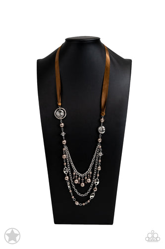 A silky brown ribbon replaces a traditional chain to give an elegant look. Pearly brown beads and funky silver pieces intermix with varying lengths of silver chains to give a fresh take on a Victorian-inspired piece.  Sold as one individual necklace. Includes one pair of matching earrings.