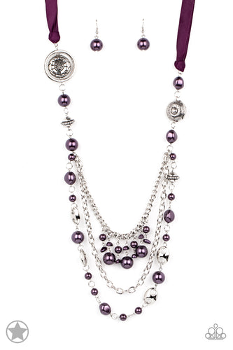 A silky purple ribbon replaces a traditional chain to create a timeless look. Pearly deep purple beads and funky silver pieces intermix with varying lengths of silver chains to give a fresh take on a Victorian-inspired piece