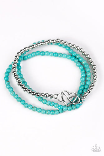 Refreshing turquoise beads and classic silver beads are threaded along elastic stretchy bands, creating colorful layers across the wrist. Brushed in an antiqued shimmer, an airy heart charm adorns the center of the silver beaded strand for a whimsical finish.  