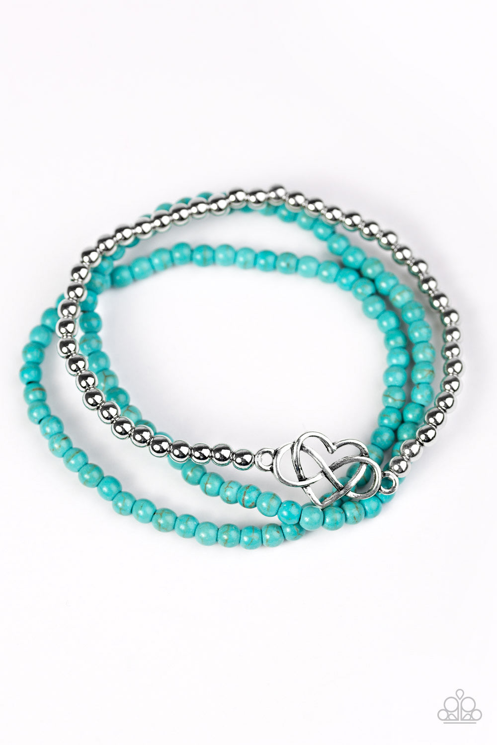 Refreshing turquoise beads and classic silver beads are threaded along elastic stretchy bands, creating colorful layers across the wrist. Brushed in an antiqued shimmer, an airy heart charm adorns the center of the silver beaded strand for a whimsical finish.  
