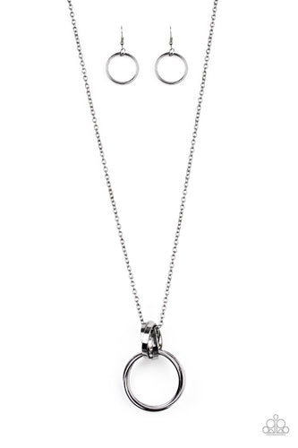 Trios of exaggerated gunmetal rings link at the bottom of a lengthened gunmetal chain, creating a dramatic industrial pendant. Features an adjustable clasp closure.