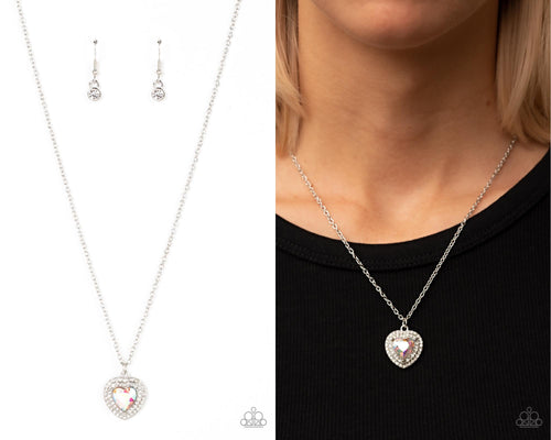 Bordered in stacked rows of glassy white rhinestones, a twinkly iridescent heart shaped gem sparkles at the center of a dainty silver chain for a flirtatious fashion. Features an adjustable clasp closure.  Sold as one individual necklace. Includes one pair of matching earrings. 