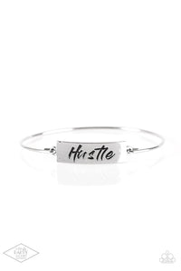 Engraved with the inspiring word "Hustle", a shimmery silver plate attaches to a skinny silver bar, creating a dainty bangle. 