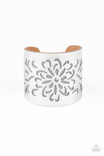 Load image into Gallery viewer, A thick piece of Ash leather peeks out beneath an airy floral pattern stenciled into a thick silver cuff, creating a whimsical display around the wrist.
