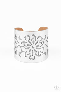 A thick piece of Ash leather peeks out beneath an airy floral pattern stenciled into a thick silver cuff, creating a whimsical display around the wrist.