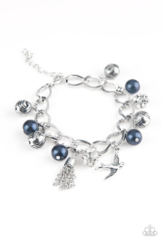 Blue pearls, ornate silver beads, and white rhinestone encrusted accents swing from a dramatic silver chain. A shimmery silver bird charm and silver tassel are added to the display, creating a whimsical fringe around the wrist. Features an adjustable clasp closure.