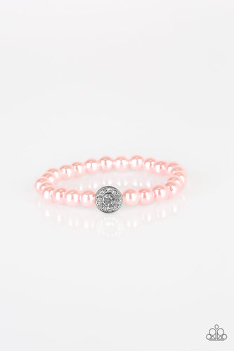 Pink pearls and a white rhinestone encrusted silver charm are threaded along a stretchy band, creating a glamorous centerpiece atop the wrist.
