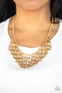 Stands of faceted gold beads and glistening gold chains stream from a matching gold chain, creating an edgy fringe below the collar. Features an adjustable clasp closure.