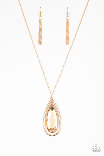 An oversized golden teardrop gem swings from the top of a glistening gold teardrop frame. The dramatic pendant swings from the bottom of an elegantly elongated gold chain for a regal finish