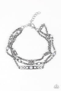 Featuring dainty gray stone accents, dainty silver triangles, round frames, and a stone studded plate trickle along three shimmery silver chains across the wrist for a seasonal look. Features an adjustable clasp closure.