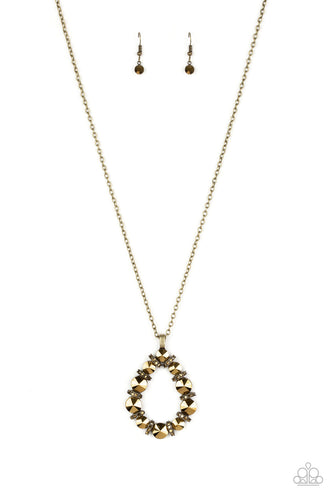Aurum rhinestone encrusted brass rings connect with oversized aurum rhinestone gems, coalescing into a dramatic pendant. The glittery teardrop pendant swings from the bottom of a lengthened brass chain in a glamorous fashion. Features an adjustable clasp closure