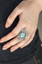 Load image into Gallery viewer, A glowing blue cat&#39;s eye stone is pressed into the center of an oval backdrop swirling with vine-like filigree for a whimsical look. Features a stretchy band for a flexible fit.
