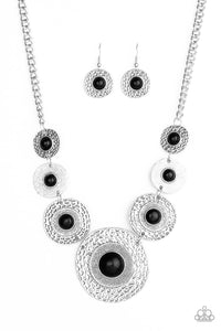 Dotted with smooth black stone centers, mismatched hammered silver frames gradually increase in size as they link below the collar for a fierce look. Features an adjustable clasp closure.