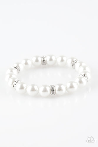Classic white pearls and glittery white rhinestone encrusted rings are threaded along a stretchy band, creating a timeless centerpiece around the wrist.