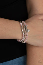 Load image into Gallery viewer, A glimmering collection of silver discs, silver cube beads, and opaque pink crystal-like beads are threaded along stretchy bands around the wrist, creating icy layers. A matching opaque crystal and white rhinestone encrusted charm swing from the display for a whimsical finish.
