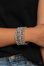 Load image into Gallery viewer, An icy collection of silver beads, silver cubes, metallic crystals, and glassy white rhinestones are threaded along a coiled wire, creating a blinding infinity wrap style bracelet around the wrist.
