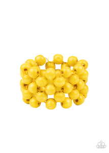An oversized collection of sunny yellow wooden beads are threaded along stretchy bands that ornately weave across the wrist, creating a decorative summery pattern.