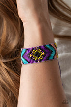 Load image into Gallery viewer, A dainty collection of purple, yellow, black, Rose Tan, and blue beads are delicately weaved into a colorful textile pattern across the wrist for a southwestern inspired fashion. Features an adjustable sliding knot closure.
