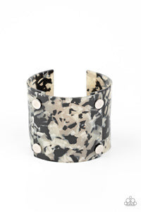 Featuring a shell-like finish, pieces of iridescent acrylic frames are bolted in place into a stylish cuff around the wrist.