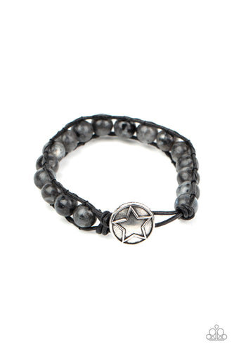 Infused with a decorative silver star embossed button, speckled black stones are threaded in place between two dainty black cords around the wrist for a seasonal fashion. Features a button loop closure.