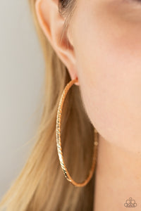 Etched in twisted diamond-cut texture, an oversized gold bar delicately curls into a dramatically oversized hoop. Earring attaches to a standard post fitting. Hoop measures approximately 2 1/2" in diameter.