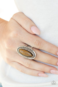 An oblong tiger's eye stone is pressed into the center of an oval silver frame stamped and embossed in mismatched patterns for a seasonal flair. Features a stretchy band for a flexible fit.