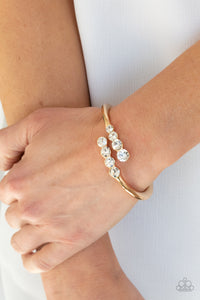 Attached to two substantial gold bars, oversized rows of glittery white rhinestones delicately stack into a hypnotizing centerpiece around the wrist. Features an adjustable hinge closure.