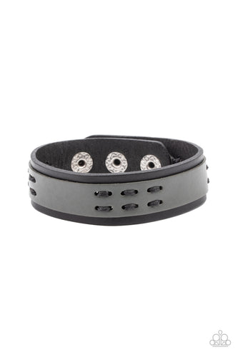 A gray leather band is stitched in place across the front of a black leather band, creating a rustic centerpiece around the wrist. Features an adjustable snap closure.