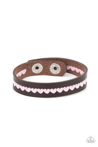 A colorful row of pink hearts is stitched across the front of a dainty brown leather band. Features an adjustable snap closure.