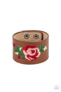 A leafy rose is embroidered across the center of a thick leather band, adding a hint of girly girl glam to the seasonal centerpiece. Features an adjustable snap closure.