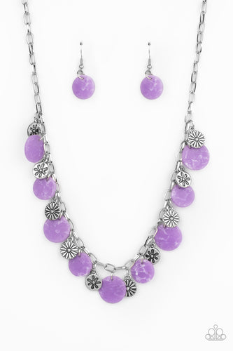 A whimsical collection of mismatched silver floral charms and purple acrylic discs swing from a silver chain, creating a vivacious fringe below the collar. Features an adjustable clasp closure.