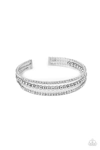 Two strands of dazzling white rhinestones flank a row of shiny silver beads, coalescing into a sparkly layered cuff around the wrist.