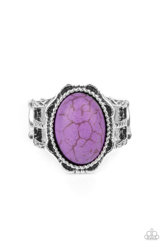 An oval purple stone is pressed into the center of a silver studded floral frame, creating a colorful centerpiece atop the finger. Features a stretchy band for a flexible fit.